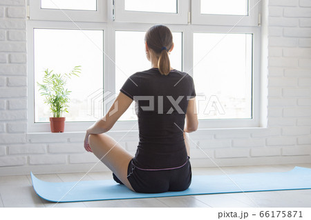 The girl sits with her back on the mat and looks The girl sits with her back on the mat and looks 66175871