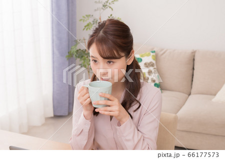 自宅でのテレワークでコーヒーを飲んで休憩する若い女性 66177573