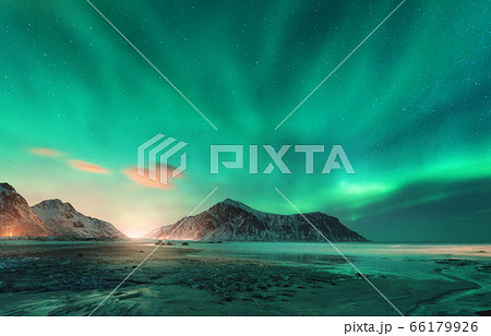 Aurora borealis above the snowy mountain and sandy beach in winter. Northern lights in Lofoten  66179926