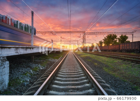 Railway station with blurred high speed train and freight train at colorful sunset. Railroad  66179930