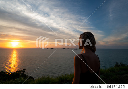 Silhouette of a woman watches sunset over a sea or ocean on a tropical island. Silhouette of a woman watches sunset over a sea or ocean on a tropical island. 66181896