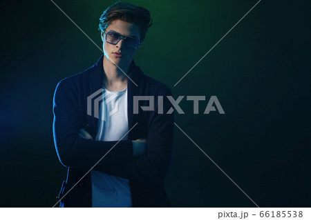 Cool stylish man in black jacket and sunglasses. High Fashion male model posing on black background. Cool stylish man in black jacket and sunglasses. High Fashion male model posing on black background. 66185538