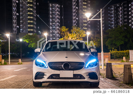 夜のドライブイメージ（白いスポーツセダン車と街並み夜景） 66186018