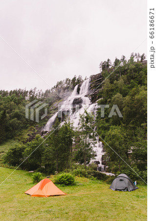 Tvinde Camping tents on the background of a waterfall Tvindefossen in Norway near Voss. Campsite in the norwegian fjords 66186671