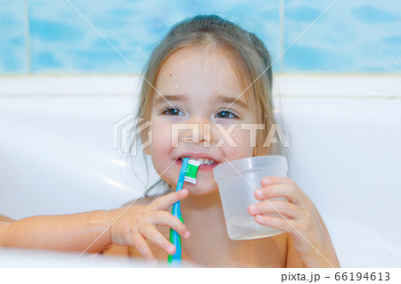 a little girl brushes her teeth and rinses her mouth in the bathroom. portrait of a child with a toothbrush a little girl brushes her teeth and rinses her mouth in the bathroom. portrait of a child with a toothbrush 66194613