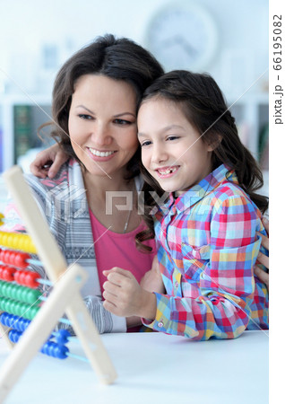 Mother teaching her daughter to use abacus indoors 66195082