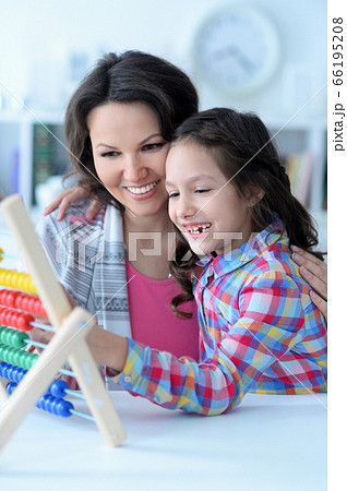 Mother teaching her daughter to use abacus indoors 66195208