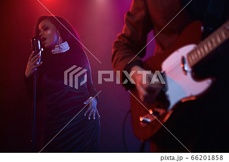 A jazz singer and guitarist perform on stage. 66201858