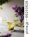 Fresh summer lemonnad with mint and kiwi stands on the table. Nearby is a bouquet of lilacs in a purple vase. 66203626