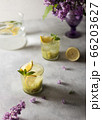 Fresh summer lemonnad with mint and kiwi stands on the table. Nearby is a bouquet of lilacs in a purple vase. 66203627