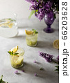Fresh summer lemonnad with mint and kiwi stands on the table. Nearby is a bouquet of lilacs in a purple vase. 66203628