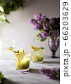 Fresh summer lemonnad with mint and kiwi stands on the table. Nearby is a bouquet of lilacs in a purple vase. 66203629