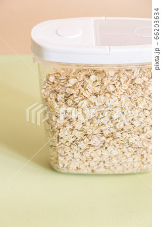 Plastic transparent container with oatmeal on a green background. Plastic transparent container with oatmeal on a green background. 66203634