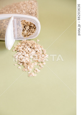 Plastic transparent container with oatmeal on a green background. Plastic transparent container with oatmeal on a green background. 66203636