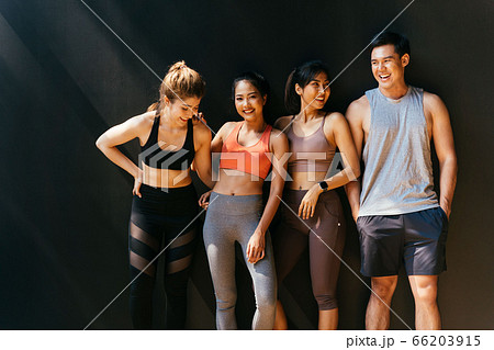 Happy smiling man and women having fun talking in gym. Group of young people relaxing in gym after workout training. 66203915