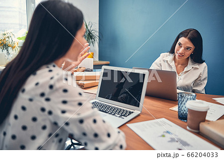 Pretty ladies sitting in office while talking Pretty ladies sitting in office while talking 66204033