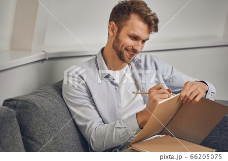 Young man taking notes in his notepad 66205075