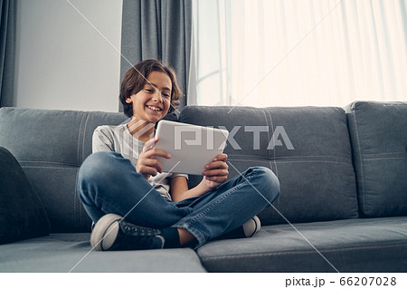 Small child sitting on the sofa and crossing legs Small child sitting on the sofa and crossing legs 66207028