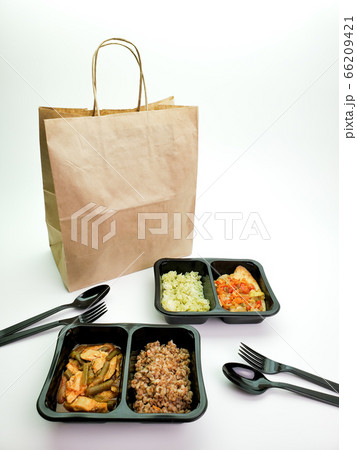 Plastic containers with delicious food and a paper bag on the table. Delivery service 66209421
