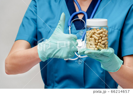 medical doctor nurse woman wearing protective mask and rubber or latex gloves - holding pills medical doctor nurse woman wearing protective mask and rubber or latex gloves - holding pills 66214657