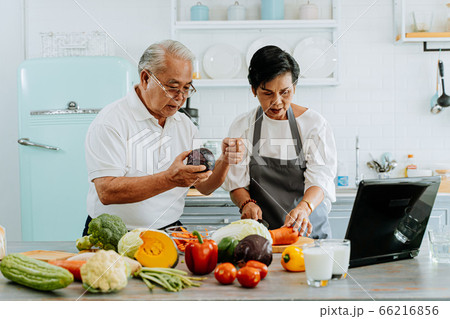Senior Asian couple using a laptop while cooking in kitchen at home. 70s Elderly man and woman in relationship retirement lifestyle concept. Senior Asian couple using a laptop while cooking in kitchen at home. 70s Elderly man and woman in relationship retirement lifestyle concept. 66216856