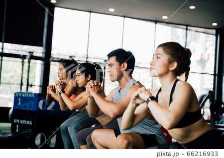 Group of athletic young Asian people in sportswear doing squat and exercising at the gym. Group of athletic young Asian people in sportswear doing squat and exercising at the gym. 66216933