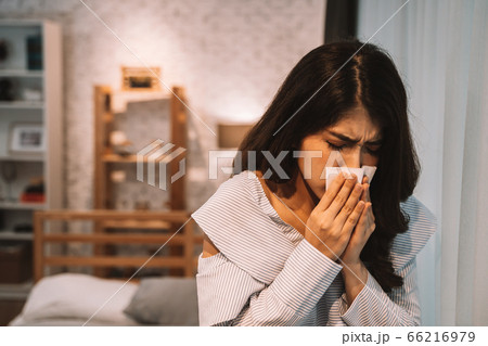 Young Asian woman suffering from cold and illness on bed with tissue at home in bedroom at night Young Asian woman suffering from cold and illness on bed with tissue at home in bedroom at night 66216979