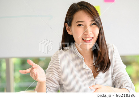 Smiling Asian woman explaining something to cemera Smiling Asian woman explaining something to cemera 66218236