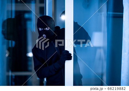 Thief breaking into apartment to steal, using torch 66219882