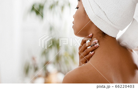 Nude african woman with towel on head touching her skin on neck Nude african woman with towel on head touching her skin on neck 66220403