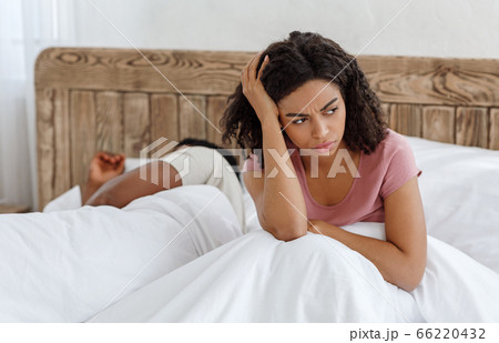 Girl sitting in bed, cant sleep because of snoring partner 66220432