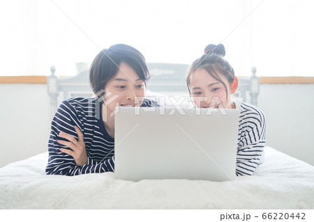 ベッドの上でパソコンを見る若いカップル ベッドの上でパソコンを見る若いカップル 66220442