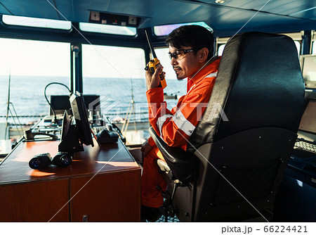 Filipino deck Officer on bridge of vessel or ship. He is speaking on GMDSS VHF radio 66224421