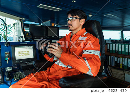 Filipino deck Officer on bridge of vessel or ship looking through binoculars 66224430