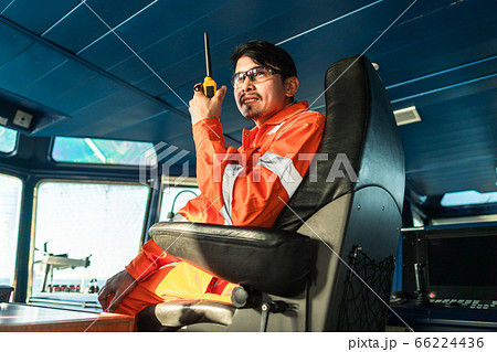Filipino deck Officer on bridge of vessel or ship. He is speaking on GMDSS VHF radio 66224436