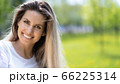 Portrait of young beautiful smiling woman on green grass in the summer outdoors 66225314