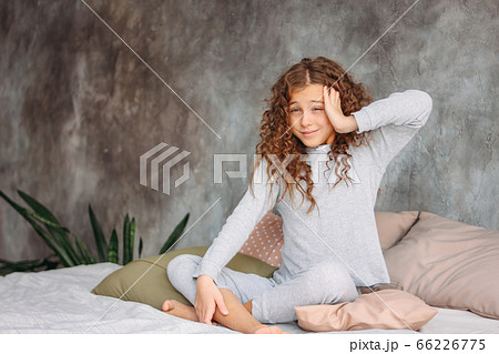 Curly haired beautiful tween girl in pajamas just waking up 66226775
