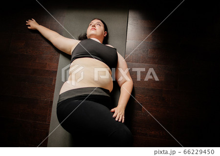 Overweight woman doing stretching exercise at home 66229450