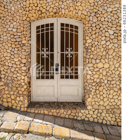 Entrance door to an old stone house decorated with pebbles. Mediterranean architecture and streets. Entrance door to an old stone house decorated with pebbles. Mediterranean architecture and streets. 66231389