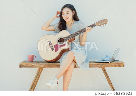 A beautiful woman playing guitar 66235922