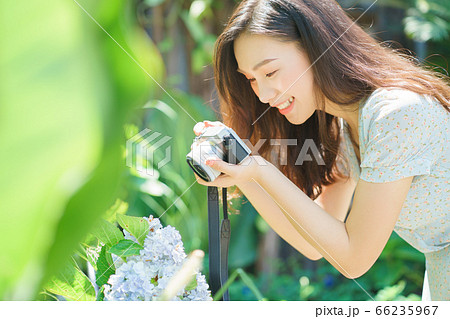 Beautiful woman holding a camera in the garden 66235967