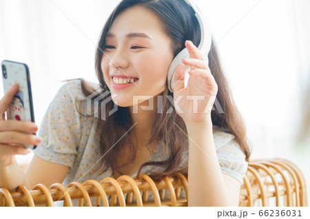Beautiful woman wearing headphone and using smartphone at home 66236031