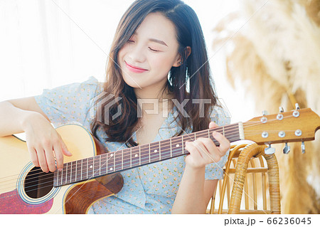 Beautiful woman playing guitar at home 66236045