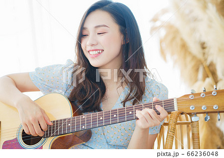 Beautiful woman playing guitar at home Beautiful woman playing guitar at home 66236048
