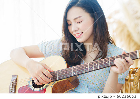 Beautiful woman playing guitar at home Beautiful woman playing guitar at home 66236053