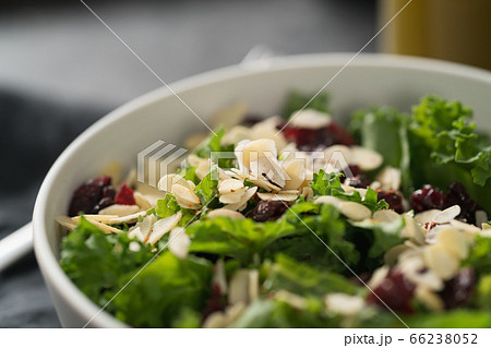 Salad with kale, cranberries and almond flakes in white bowl closeup 66238052