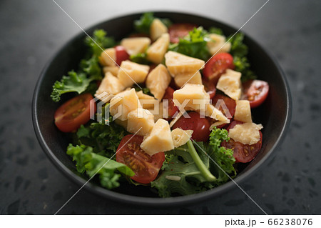 Salad with cherry tomatoes, kale and cheese in black bowl on concrete background Salad with cherry tomatoes, kale and cheese in black bowl on concrete background 66238076
