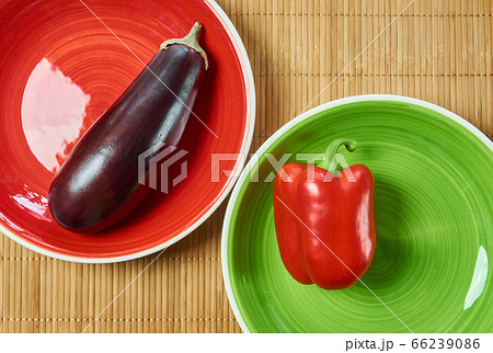 purple eggplant on a red plate and red bell pepper 66239086