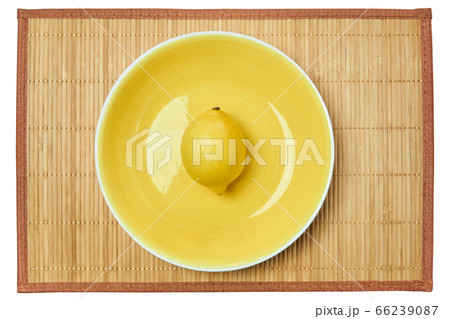 bright yellow lemon on a yellow plate on a cane 66239087