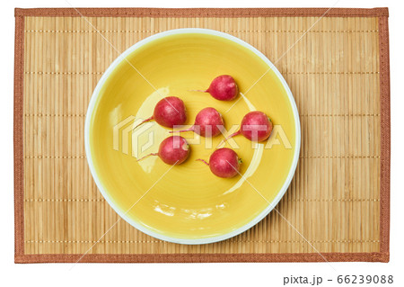 five red radishes on a yellow plate on a cane 66239088